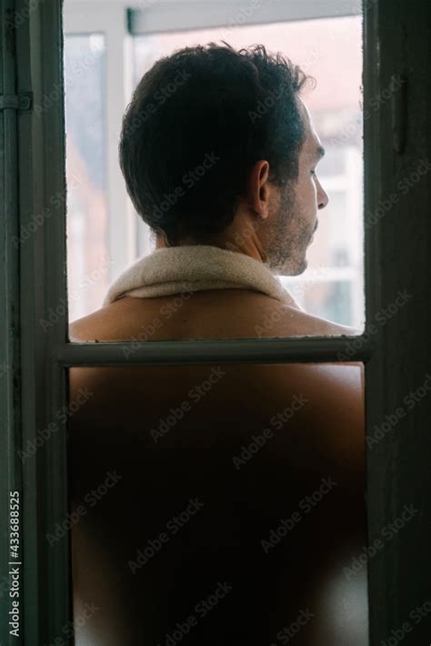 Back View Of Male With Naked Torso Standing Near Window At Home And Closed Eyes Stock Foto