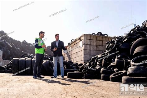 Mature Businessman Discussing Over Rubber Tires With Colleague Stock
