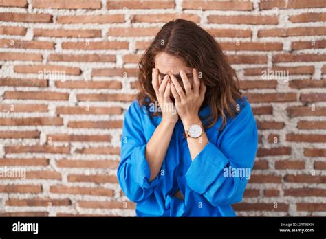 Beautiful Brunette Woman Standing Over Bricks Wall With Sad Expression Covering Face With Hands