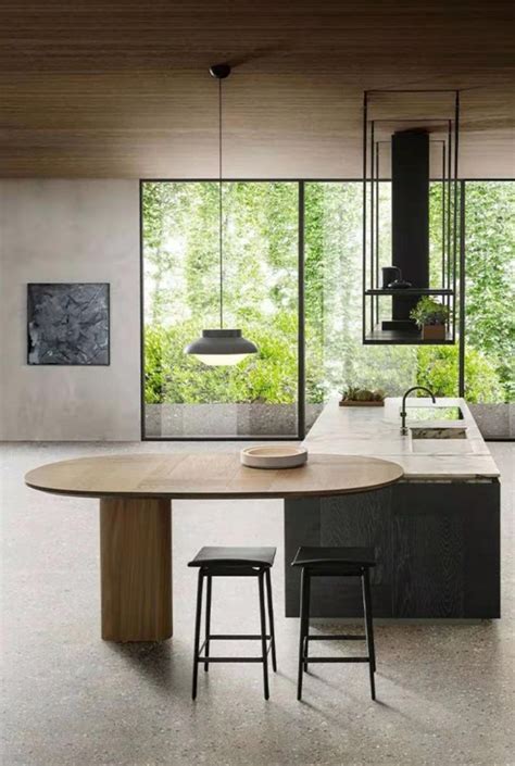 A Kitchen With An Island Table Surrounded By Stools And Plants In The