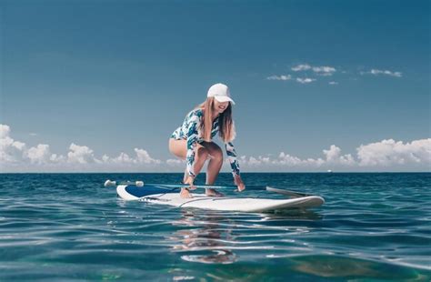 Mujer sana feliz en forma de bikini relajándose en una tabla de surf sup flotando en el mar