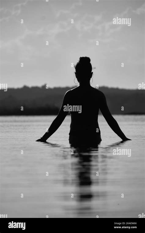 A Vertical Grayscale Shot Of The Woman S Silhouette On The Water S