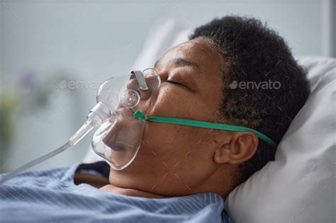 Senior Woman Sleeping On Bed In Hospital With Oxygen Support Mask Stock