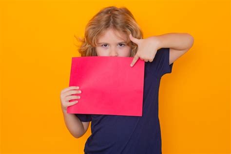 Niño señalando una hoja de papel vacía aislada en un retrato de fondo