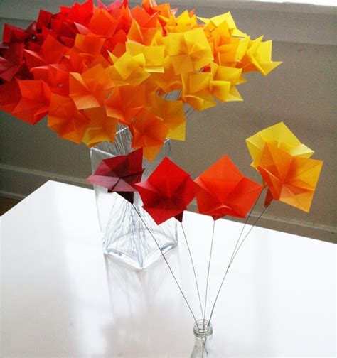 A Vase Filled With Colorful Origami Flowers On Top Of A White Table Next To A Window