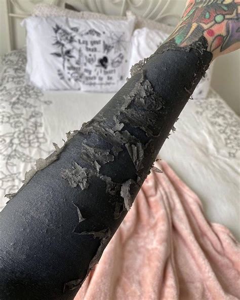 A Person With Tattoos On Their Arm Holding Up A Black Piece Of Fabric