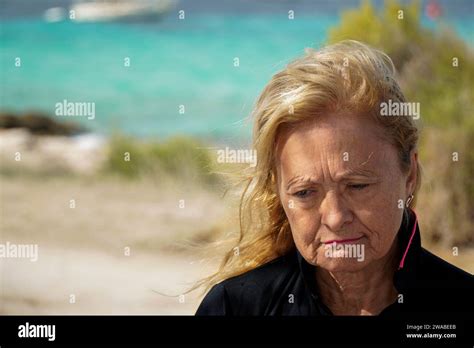 Close Up Portrait Of A Sad Mature Woman In A Windy Beach Looking Down