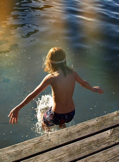 Premium Photo Rear View Of Shirtless Boy Jumping To Lake