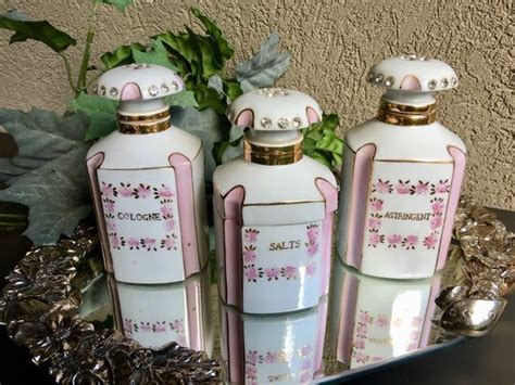 Three Pink And White Ceramic Bottles With Gold Trimmings On The Top