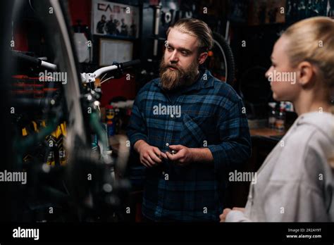 Beau réparateur cycliste ayant eu une conversation avec une cliente blonde parlant du problème