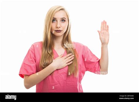 Portrait Of Young Female Nurse Wearing Scrubs Taking Oath Isolated On