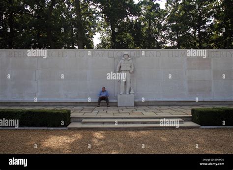 A Man Sits Reading Beside A Coastguard Memorial Statue On The Wall Of