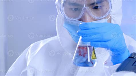 Scientist In Ppe Suite Doing Some Research Checking A Liquid In A Test