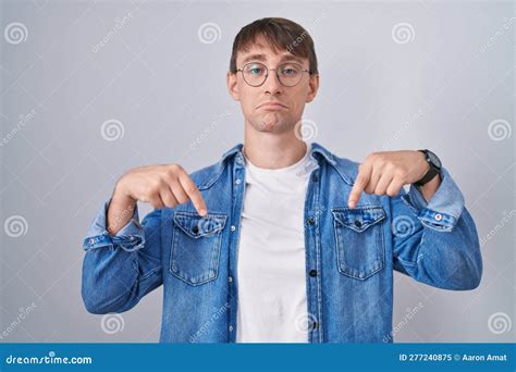 Caucasian Blond Man Standing Wearing Glasses Pointing Down Looking Sad