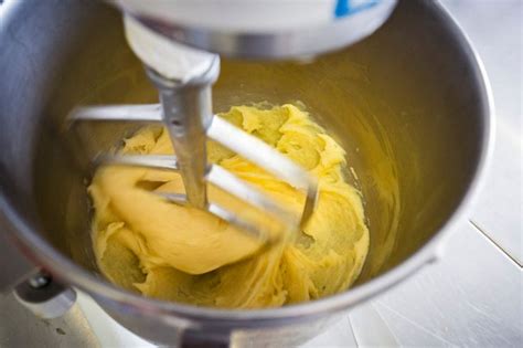 A Mixer Filled With Yellow Batter On Top Of A Counter