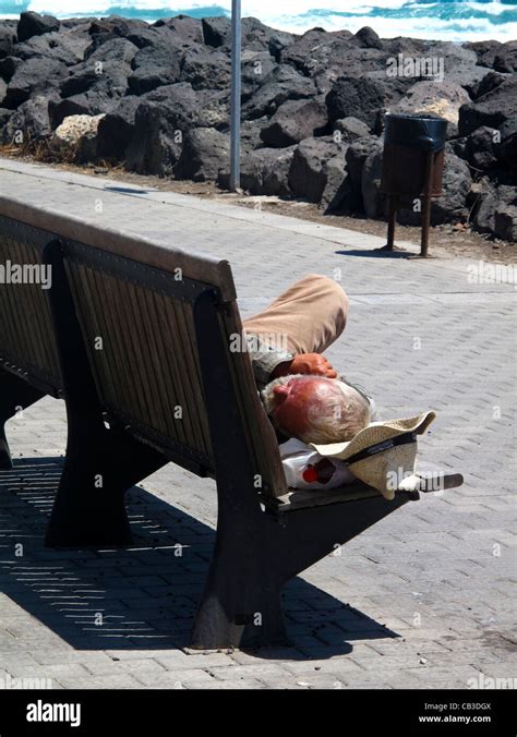 Tramp sleeping on wooden bench in sunshine Stock Photo - Alamy