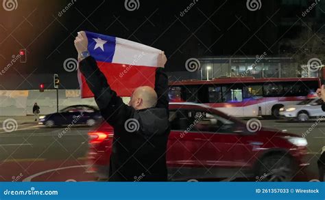 A Bald Chilean Man Whose Face We Cannot See Holds Up A Chilean Flag To