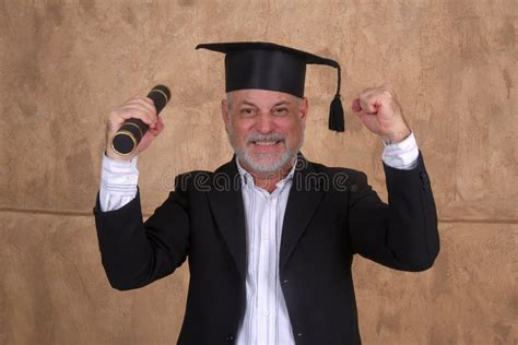 Mature Man In A Graduation Gown Holding A Diploma And Celebrating Stock