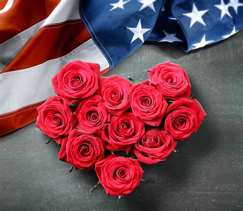 A Bunch Of Red Roses In The Shape Of A Heart Next To An American Flag