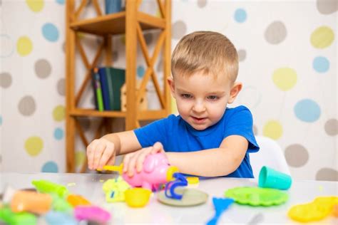 Premium Photo Cute Child Sitting At The Table And Plays With Playdough