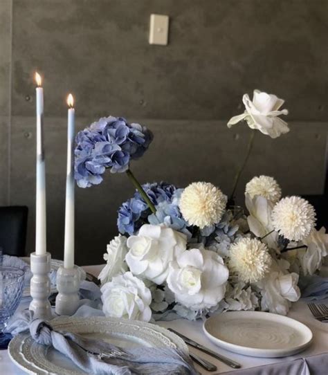 The Table Is Set With Blue And White Flowers Plates And Candles On It