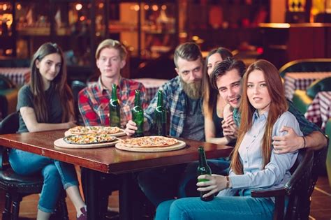 Amigos tomando una copa en un bar están sentados en una mesa de madera