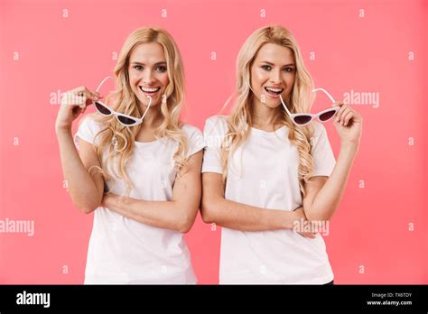Playful Blonde Twins Wearing In T Shirts Posing With Sunglasses Together And Looking At The