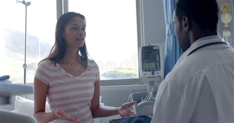 Diverse Female Patient And Male Doctor Talking Standing In Hospital