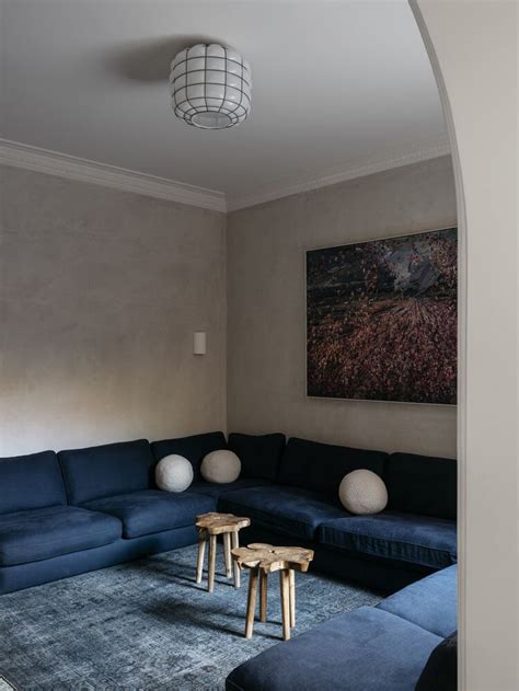 A Living Room With Blue Couches And Two Stools In Front Of A Painting