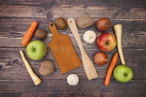 Onion Apples Carrot And Kiwi With Cutting Board On Wooden Table Stock