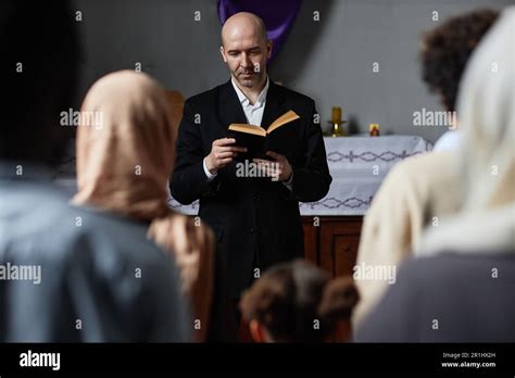 Mature Preacher In Black Suit Reading Bible For Believers Standing Near The Altar In Baptist