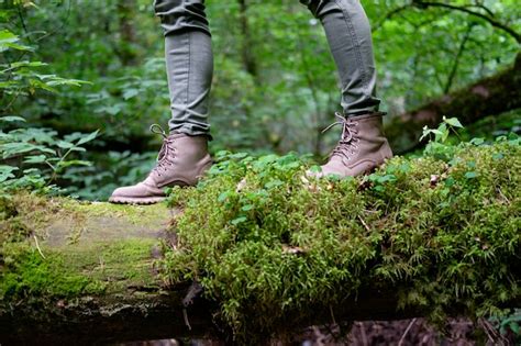 Os Pés Da Mulher Em Botas De Viagem Em Um Tronco Musgoso Na Floresta Conceito De Viagens