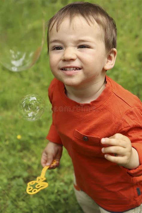 A Little Boy Plays With Soap Bubbles In The Summer Stock Image