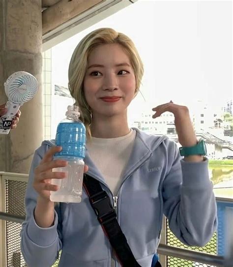 A Woman Is Holding A Water Bottle And Posing For The Camera With Her