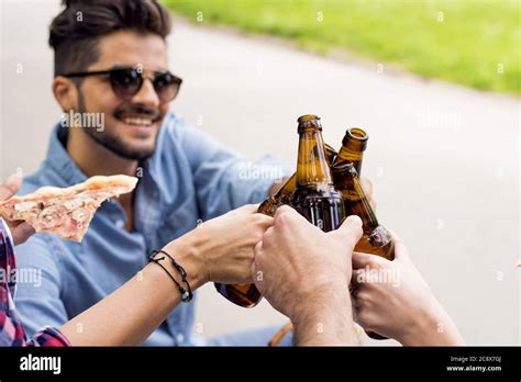 Sunny Scenery Of A Group Of Caucasian Friends Toasting With Their Beer Bottles In A Park Stock