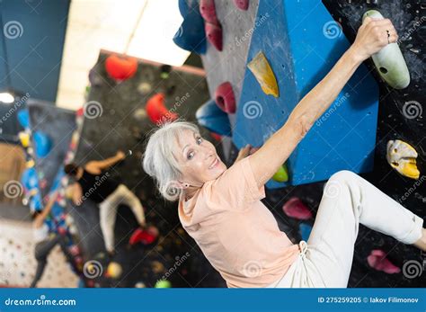 Positive Focused Mature Woman Exercising On Black Climbing Wall Without