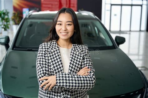 Beautiful Brunette Stands Against The Backdrop Of Sparkling New Car