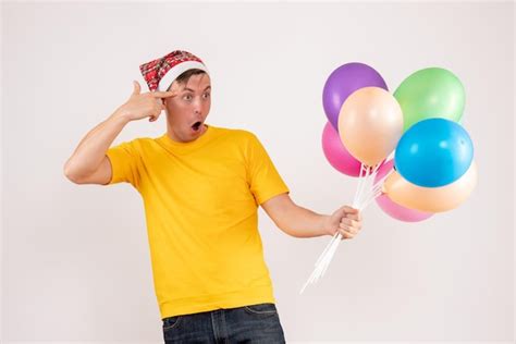 Vista Frontal Del Joven Sosteniendo Globos De Colores En La Pared