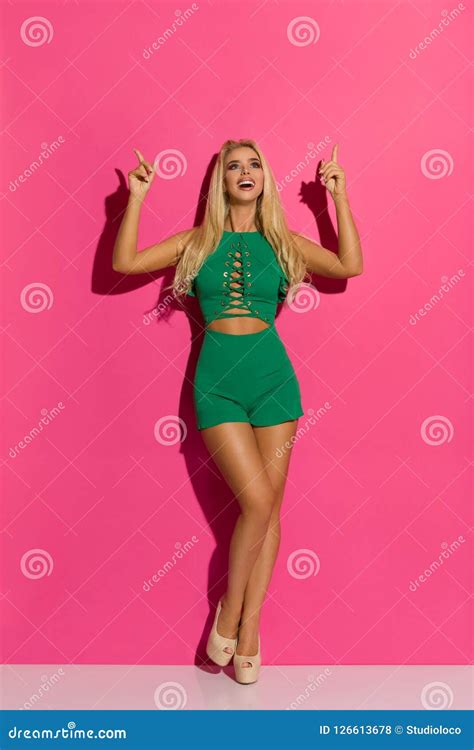 La Femme Blonde Sexy Dans La Salopette Et Des Talons Hauts Courts Verts Se Dirige Et Rire Photo