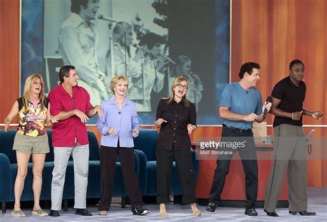 five people standing in front of a projector screen and one person holding a microphone