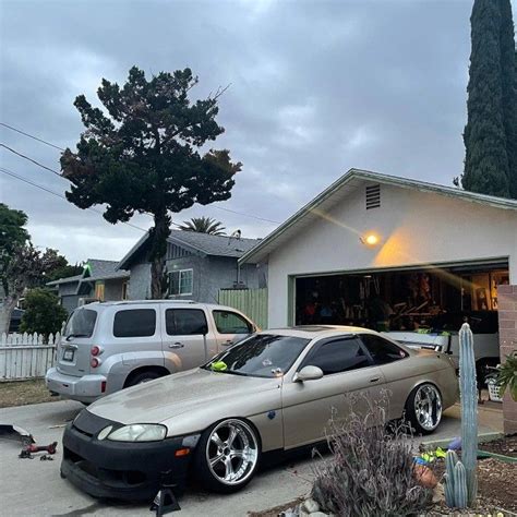 Two Cars Parked In Front Of A House With The Garage Door Open And One