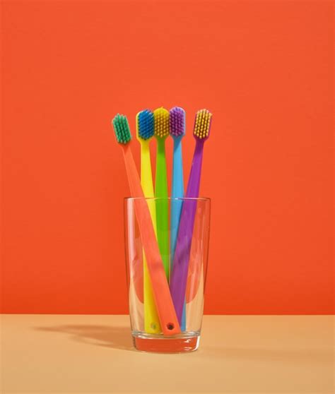 Premium Photo Toothbrushes Of Different Colors Stand In A Glass On An