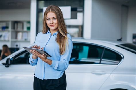 Free Photo | Female salesperson at a car showroom by the car