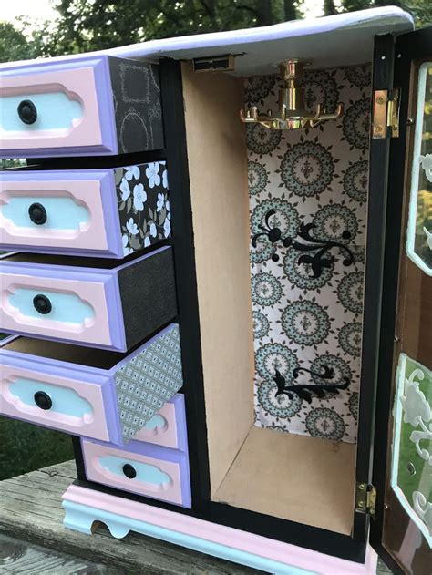 An Old Dresser Is Painted In Pink Purple And Black With Ornate Designs