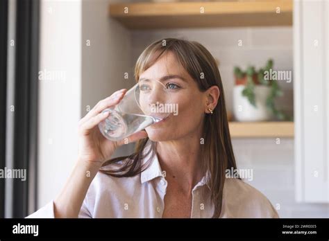 Caucasian Woman Drinks Water In A Kitchen She Appears Hydrated And