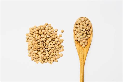 Dry Seeds Of Pardin Lentils In A Wooden Spoon And Sprinkled On A White