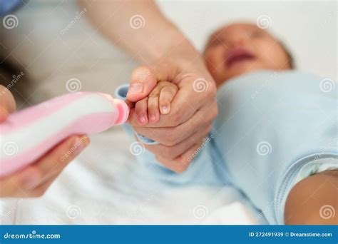 Mother Cutting Baby S Fingernails With Auto Electic Nail Trimmer Stock