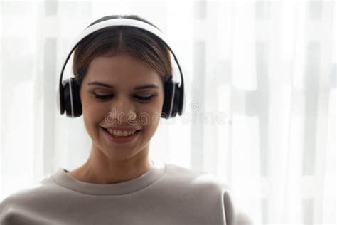 Happy Young Woman Wearing Headphones Listening Music While Using Laptop