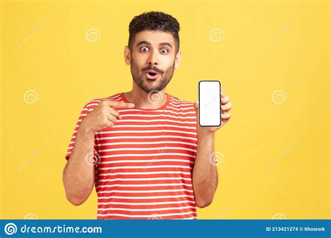 Surprised Bearded Man In Striped T Shirt Pointing Finger At Smartphone