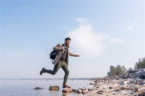 Viajero Masculino Joven Con Su Mochila Que Se Ejecuta Sobre Las Piedras